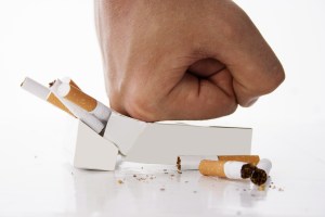 Hand crushing cigarettes over white background